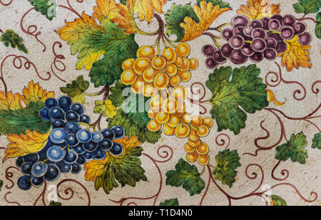 Hand-painted traditional Italian majolica ceramic texture with grape clusters, green leaves and fine craquelure glaze detail Stock Photo