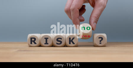 Taking a risk? Hand turns a dice and changes the word 'yes' to 'no'. Stock Photo