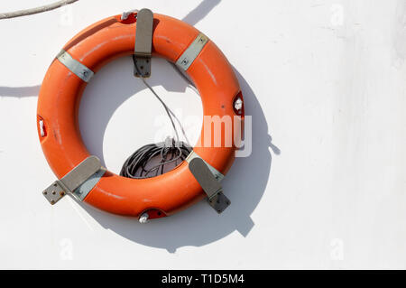 Red emergency lifebuoy hanging on the side of a fishing boat. Stock Photo