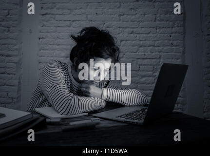 Black and white portrait of a pensive and tired female student working late at night on her laptop. Feeling fatigued and trying to concentrate and kee Stock Photo