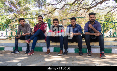 Five young Indian men sitting on the sidewalk Stock Photo
