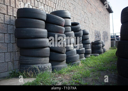 Rubber Industry Stacked Used Tires Against Brick Wall Stock Photo