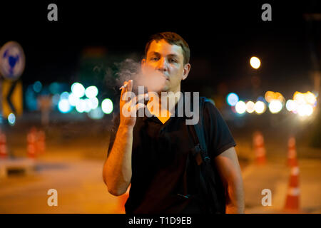 man smoking a cigarette on the street at night. Stock Photo