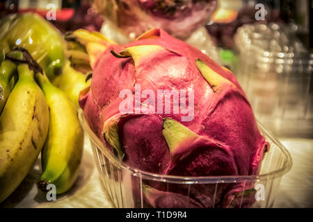 A close-up of a dragon fruit in a plastic box at the marketplace Stock Photo