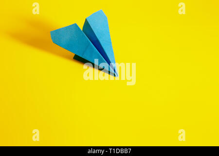 blue paper airplane on a yellow background, with long shadows Stock Photo
