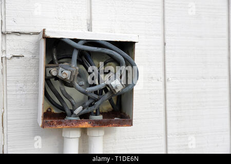 Old electrical connection panel or box on outside of building, wires exposed Stock Photo