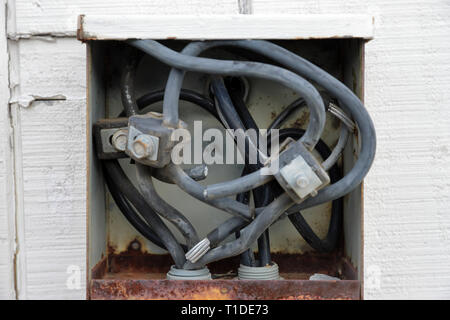 Old electrical connection panel or box on outside of building, wires exposed Stock Photo