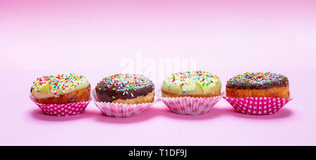 Cupcakes on pink. Mini cakes with icing and colorful sprinkles on pink background, closeup view, banner Stock Photo