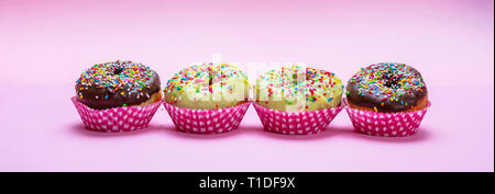 Cupcakes on pink. Mini cakes with icing and colorful sprinkles on pink background, closeup view, banner Stock Photo