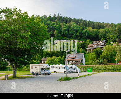 Schiltach, Germany - Jul 10, 2018: Couple resting in Chaise longue chairs in front of multiple RV camping recreational camping vehicles vans parked on the open air parking in the heart of black forest mountains in schiltach village Stock Photo