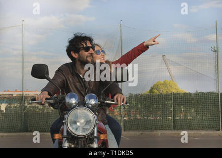 Couple of motorcyclists on a retro style motorcycle, looking at the blue sky. Woman pointing with her arm towards the sky in Spain Stock Photo
