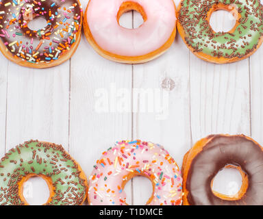 Colorful donuts with icing on wood background. Stock Photo