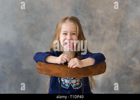 Little girl holding two little red hearts. The concept of Valentine's Day. gray background. Stock Photo