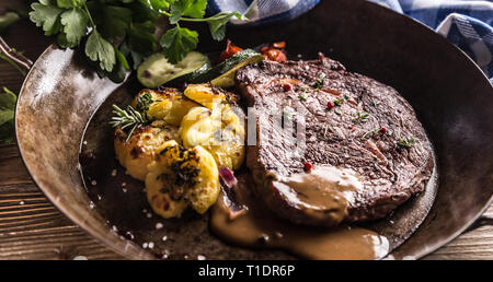 Juicy beef Rib Eye steak roasted potatoes with sauce grilled vegetable salt pepper and herbs in vintage pan. Stock Photo