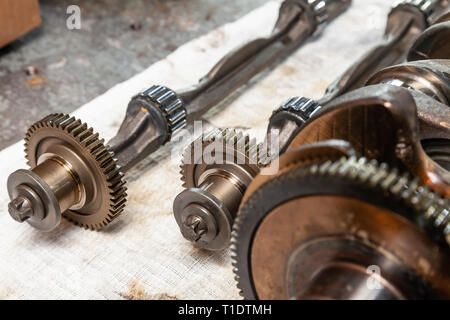 Close-up on a car shaft with gears and bearings removed for replacement on a workbench in a repair shop for vehicles. Auto service industry. Stock Photo