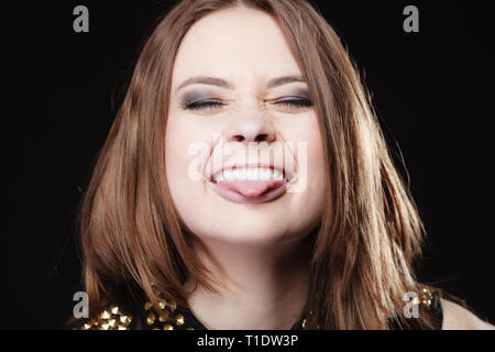Young people teenage concept - teen funny girl making silly face sticking tongue on black Stock Photo
