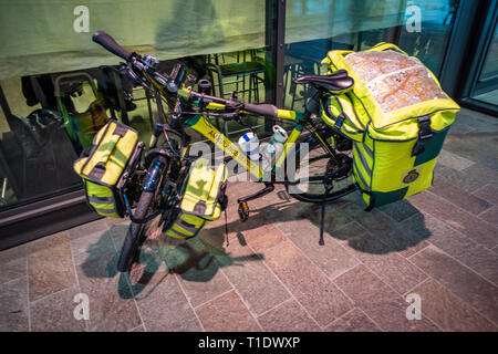 Looking from above at a Paramedic emergency push bike, a custom-built bicycle, medical kit and specialist clothing parked on its bike stand outside a Stock Photo