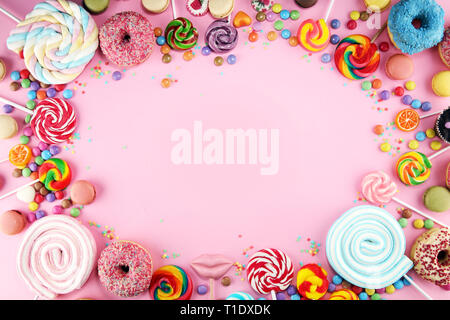 candies with jelly and sugar. colorful array of different childs sweets and treats on pink background Stock Photo