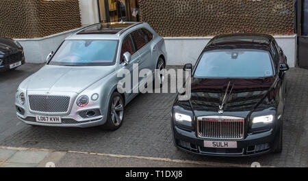 one black Rolls Royce and a silver Bentley Bentayga two executive cars parked in VIP parking area outside a top London Hotel Stock Photo