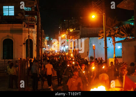 Santa Clara, Cuba - January 27 2019: Thousands of people marching down the street holding in their hands torches lit at night Stock Photo