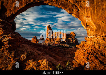 Fog rolls across Turret Arch in Arches National Park viewed through  north window Stock Photo