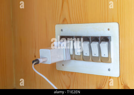 An Indian pin USB charger inserted into a wall socket with switches Stock Photo