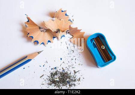 A pencil sharpened with a sharpener with pencil peels and black graphite lead waste on a white background Stock Photo