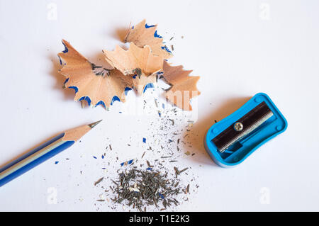 A pencil sharpened with a sharpener with pencil peels and black graphite waste on a white background Stock Photo