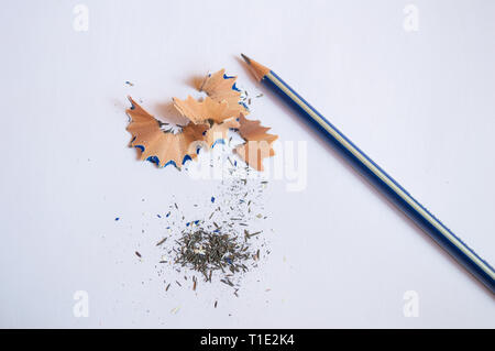 A pencil sharpened with pencil peels and black graphite lead waste on a white background Stock Photo