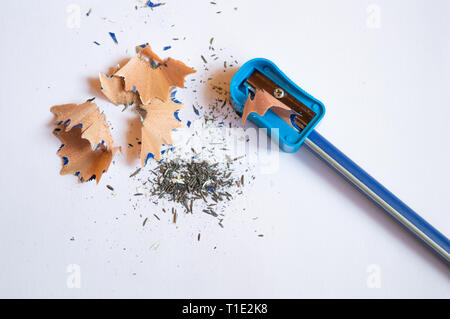 A pencil sharpened with a sharpener with pencil peels and black graphite lead waste on a white background copy space Stock Photo