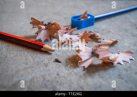 A pencil sharpened with a sharpener with pencil peels. Other pencil nib broken and lying on table Stock Photo