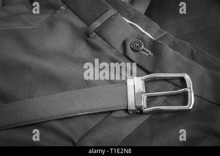 Black and white view of black leather belt kept on a formal pant trouser Stock Photo