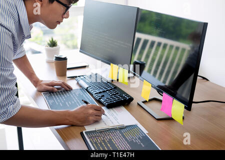 Serious busy hipster young web software developer programmer is coding or programming on a desktop computer information in modern office technologies  Stock Photo
