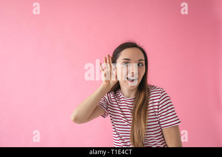 A girl holding her hand next to her ear. The concept of chatter, gossip, news or secrets. Stock Photo
