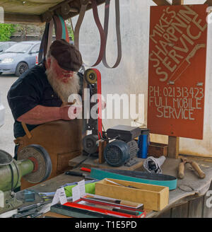 A knife sharpener tradesman at work at the Matakana Farmers Market, Matakana, New Zealand. Stock Photo