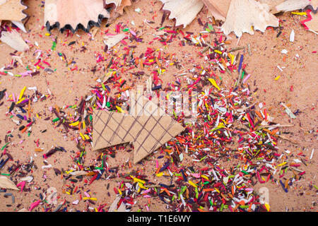 Arrow cut out of paper amid pencil shavings on canvas Stock Photo