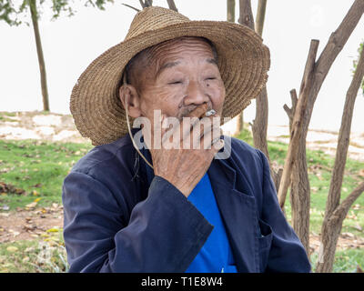 portrait of a Local mature man smoking at a small village in the mountains near Kumming, Yunnan province in southwest China in September Stock Photo