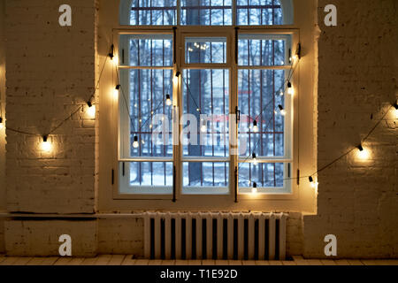 light bulbs hang on long wires on the background of a beige wooden closet inside the room Stock Photo