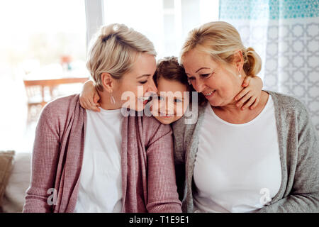 A portrait of small girl with mother and grandmother at home. Stock Photo