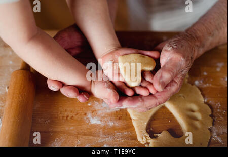 Midsection of grandmother with small toddler boy making cakes at home. Stock Photo