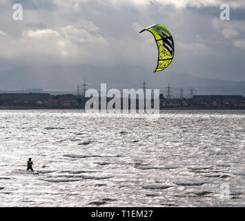East Lothian, Scotland, United Kingdom, 26 March 2019. UK Weather: Kitesurfing at Longniddry Bents. A solitary kitesurfer with a bright yellow kite takes advantage of the stiff breeze in the Firth of Forth Stock Photo