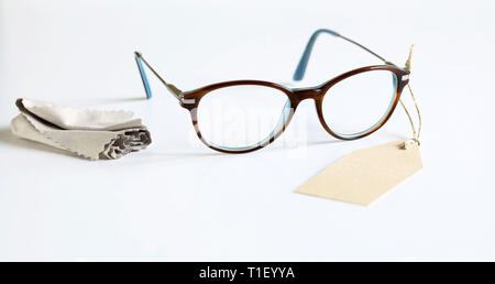 Closeup of eyeglasses and lens cloth with empty tag isolated on white background Stock Photo