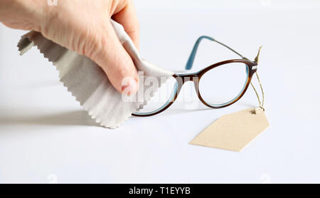 Woman hands with eyeglasses and lens cloth on white background. Empty tag Stock Photo