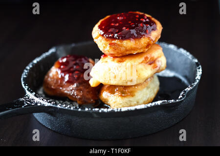 Stack Russian homemade yeast pancakes with organic Raspberry jam in cast iron skillet. Breakfast concept. Stock Photo