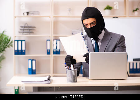 Male gangster stealing information from the office Stock Photo
