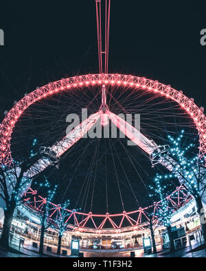 London, United Kingdom: London Eye at night, as seen from the Belvedere Rd., with a foreground of trees lit up by blue tiny lights. Stock Photo