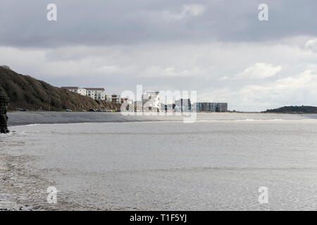 Sun breaks through the clouds and shines on the flats and pebble beach at the Knap, Barry, South Wales. Stock Photo