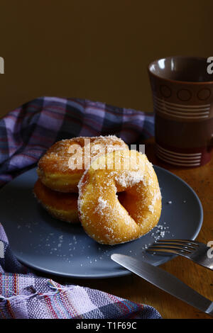 Photo of sugar raised or sugar flavored donuts on a plate and a coffee mug. Stock Photo