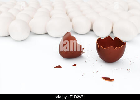One chocolate egg broken on two pieces. Chocolate egg around white eggs, concept individuality, exclusivity. Sweet yummy chocolate egg. Symbol of holi Stock Photo