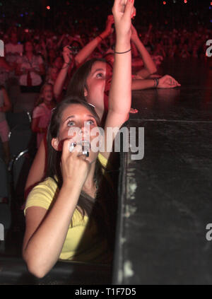 Front row concert fans are shown with amazement on their faces while watching a 'live' performance. Stock Photo